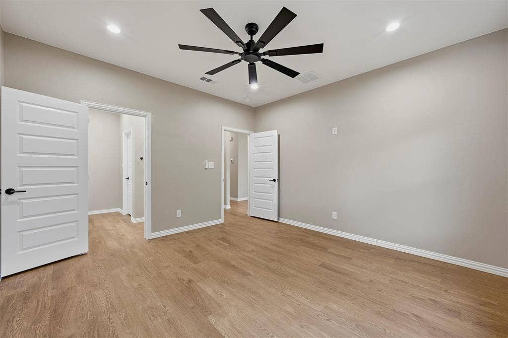 Wood-finish flooring, recessed lighting, matte black multi-blade ceiling fan, and six-panel interior doors with matte black hardware