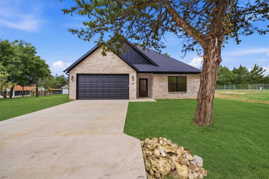 Stone and vertical siding exterior featuring a multi-gable roofline, attached two-car garage, and concrete driveway