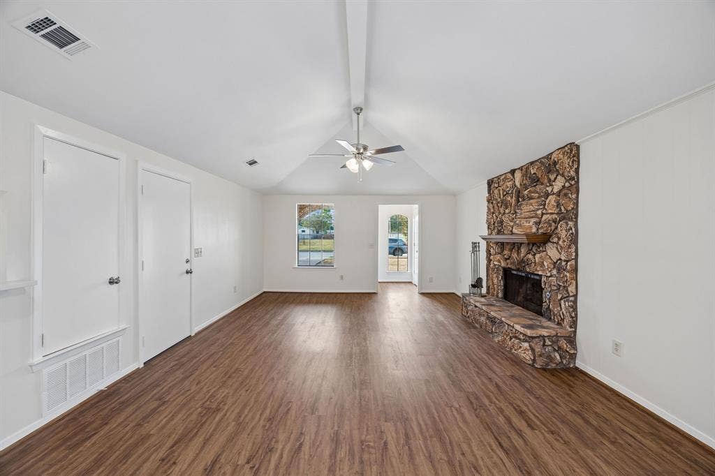 1613 19th Street, Plano, TX 75074 Vaulted ceiling, wood-finish flooring, stone-clad fireplace with mantel, ceiling fan, and white interior doors
