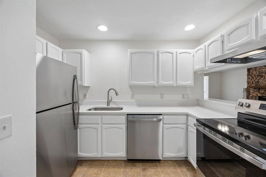 1613 19th Street, Plano, TX 75074 White cabinetry with brushed nickel hardware, stainless steel appliances, a stainless steel sink with a gooseneck faucet, and recessed lighting