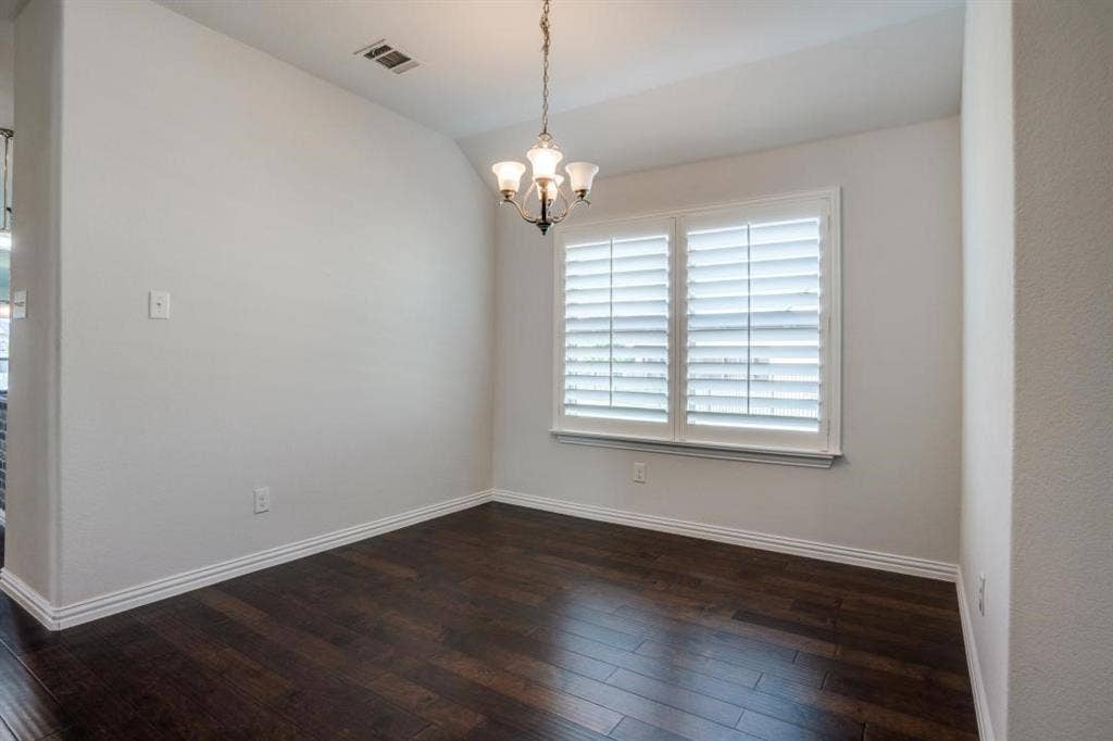 6229 Gloucester Drive, Celina, TX 76227 Dark wood-finish flooring, white plantation shutters, white crown molding, and a three-light chandelier