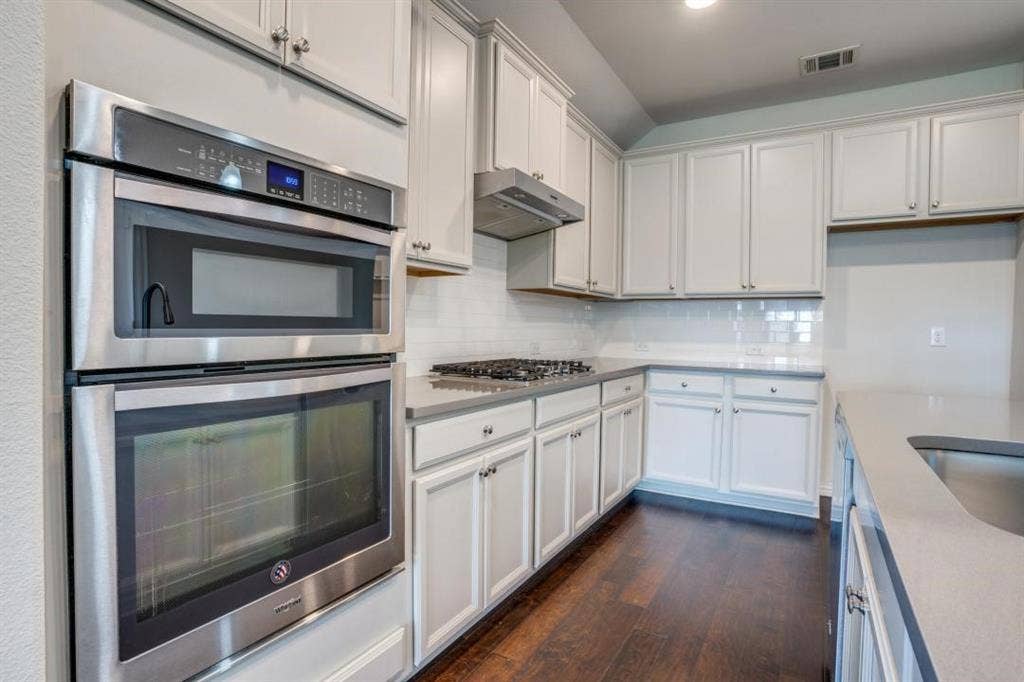 6229 Gloucester Drive, Celina, TX 76227 Kitchen featuring light-toned cabinetry, stainless steel built-in appliances, a gas range with a range hood, light-toned countertops, and dark wood-finish flooring