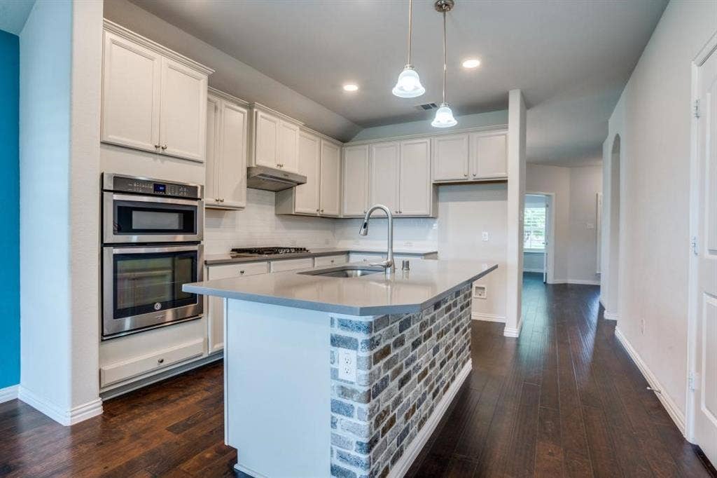 6229 Gloucester Drive, Celina, TX 76227 Kitchen featuring light cabinetry, stainless steel appliances, a center island with brick detailing, wood-finish flooring, and pendant lighting