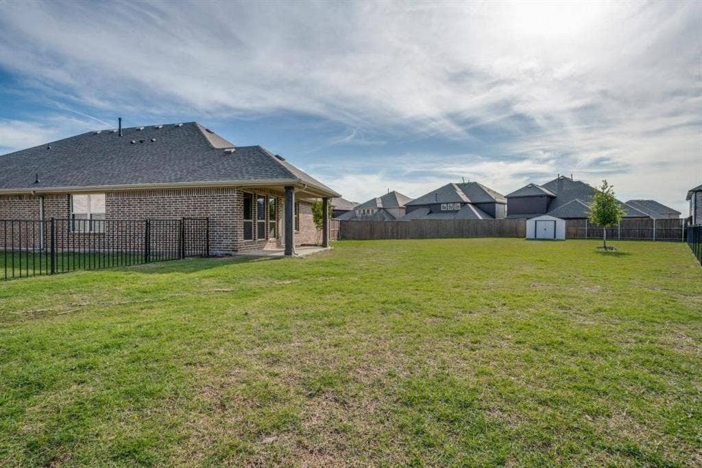 6229 Gloucester Drive, Celina, TX 76227 Expansive grassy lawn with a privacy fence, covered patio, and a storage shed