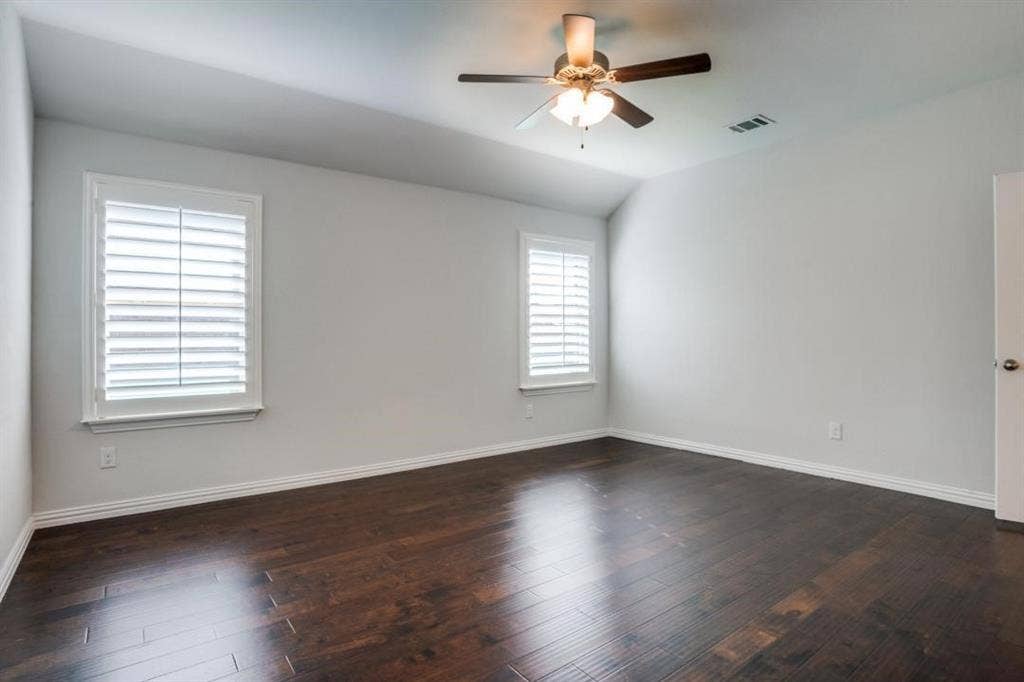 6229 Gloucester Drive, Celina, TX 76227 Vaulted ceiling with a ceiling fan, two windows with plantation shutters, and wood-finish flooring