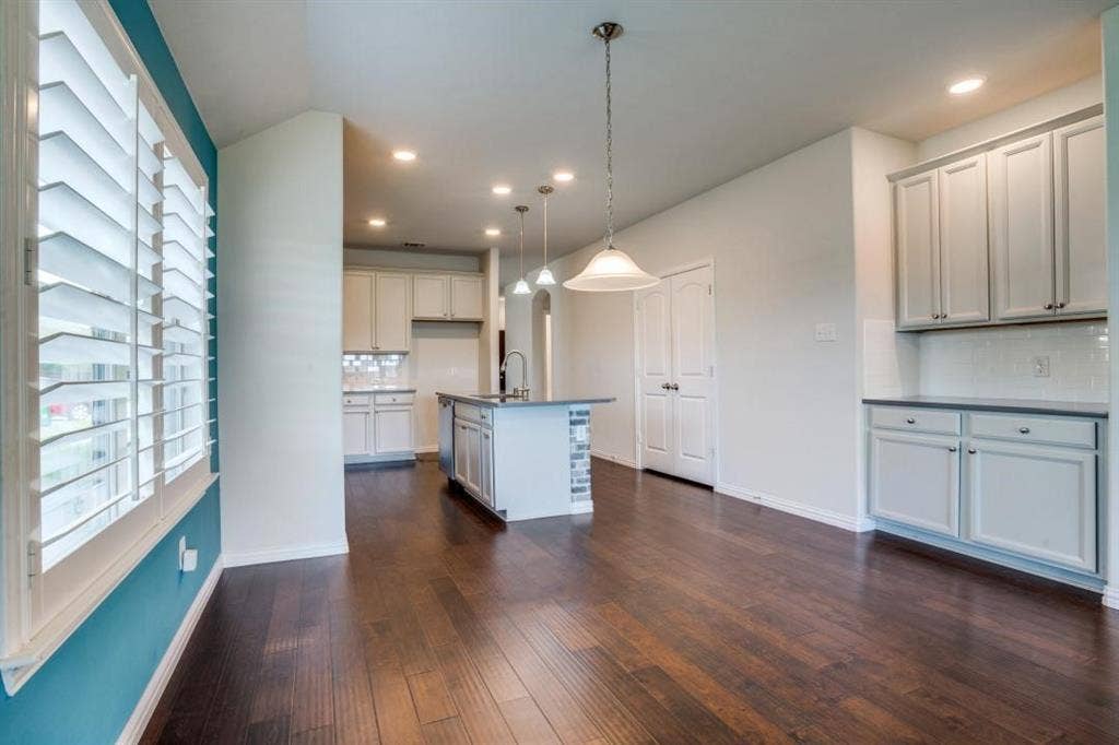 6229 Gloucester Drive, Celina, TX 76227 Hardwood flooring throughout, white cabinetry with dark countertops, recessed lighting, white subway tile backsplash, and plantation shutters