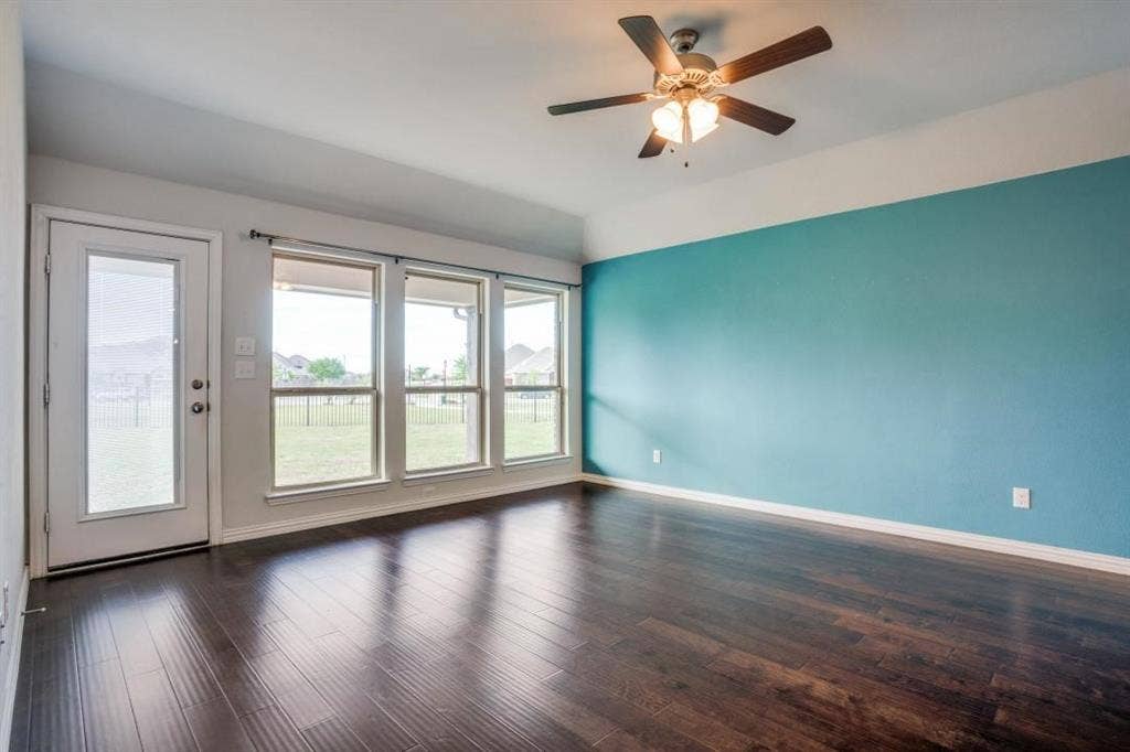 6229 Gloucester Drive, Celina, TX 76227 Dark wood-finish flooring, a ceiling fan with integrated lighting, and multiple windows with transoms