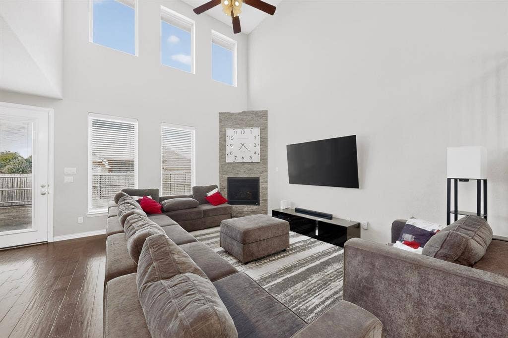 20 foot Vaulted ceiling with a ceiling fan, dark wood-finish flooring, stone-clad fireplace, and transom windows