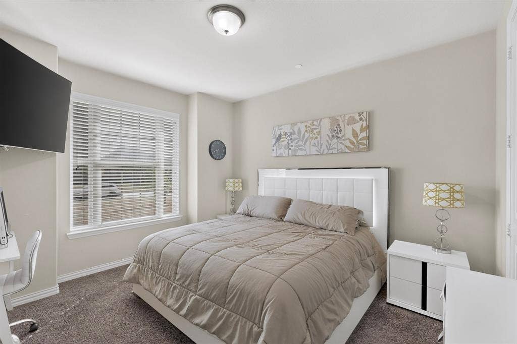 Downstairs Carpeted room with a ceiling-mounted light fixture, a window with blinds, and a built-in wall niche