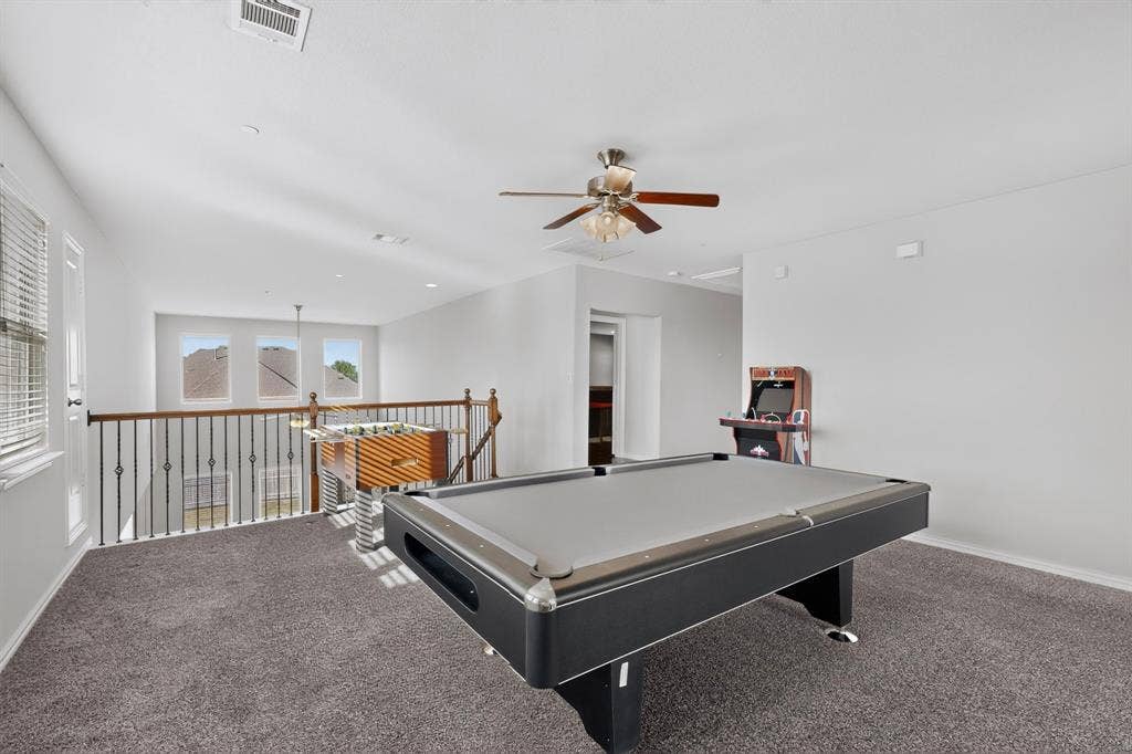 Spacious upper-level landing with plush carpet flooring, a ceiling fan, and abundant natural light from multiple windows