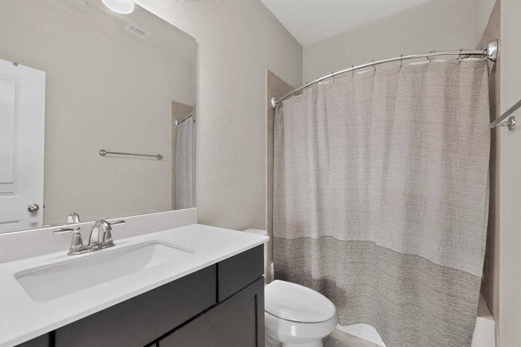 Bathroom featuring a rectangular undermount sink, dual-handle chrome faucet, dark wood-finish vanity, and a curved shower rod