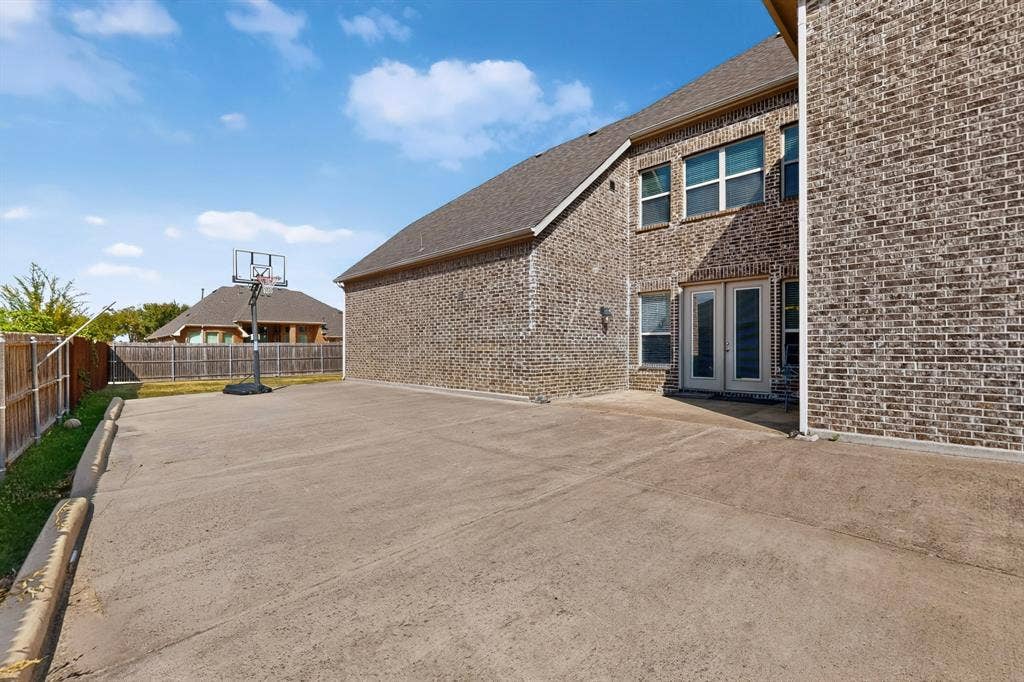 Brick exterior with multiple windows, concrete patio, and a privacy fence