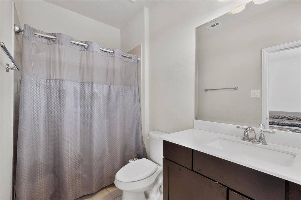Bathroom featuring a single vanity with a white countertop, chrome faucet, and integrated sink