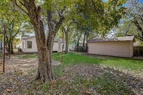 7729 Hillard Drive, Dallas, TX 75217 Expansive backyard featuring a large mature tree, a detached utility building, and a wood privacy fence