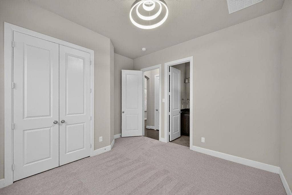 Neutral-toned interior space featuring carpeting, a multi-tiered circular light fixture, and two-panel interior doors