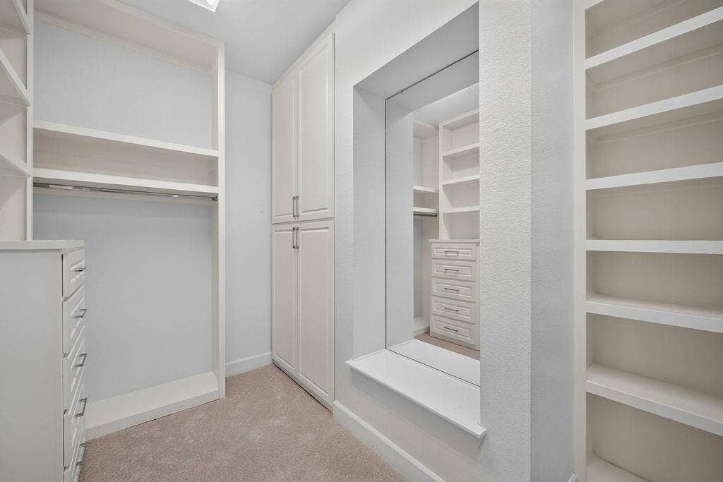 Custom built-in cabinetry featuring floor-to-ceiling storage, open shelving, integrated drawers, and a central full-length mirror with a display ledge