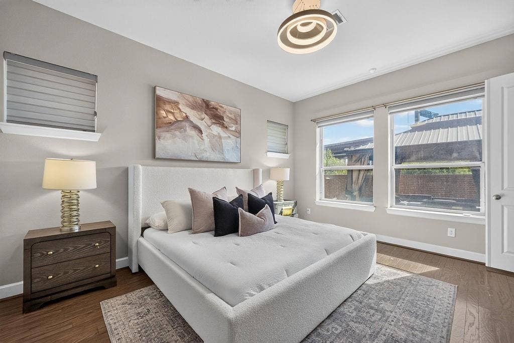 Neutral-toned walls featuring wood-finish flooring, dual windows, and a modern circular semi-flush mount light fixture
