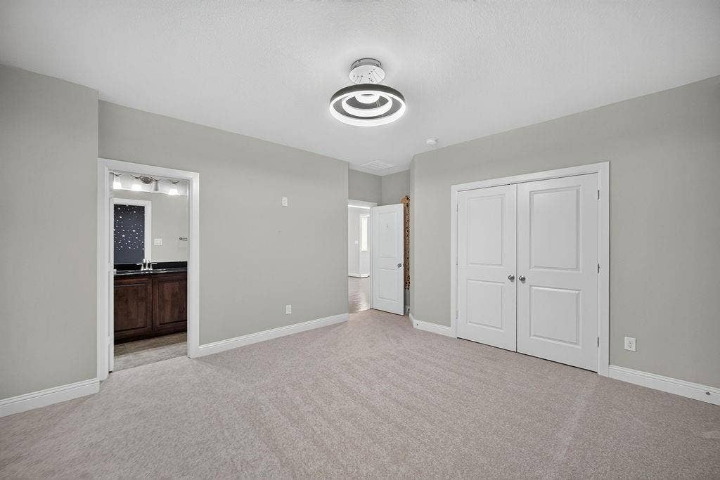 Neutral-toned interior featuring wall-to-wall carpeting, modern circular flush-mount lighting, double-panel closet doors, and interior paneled doors