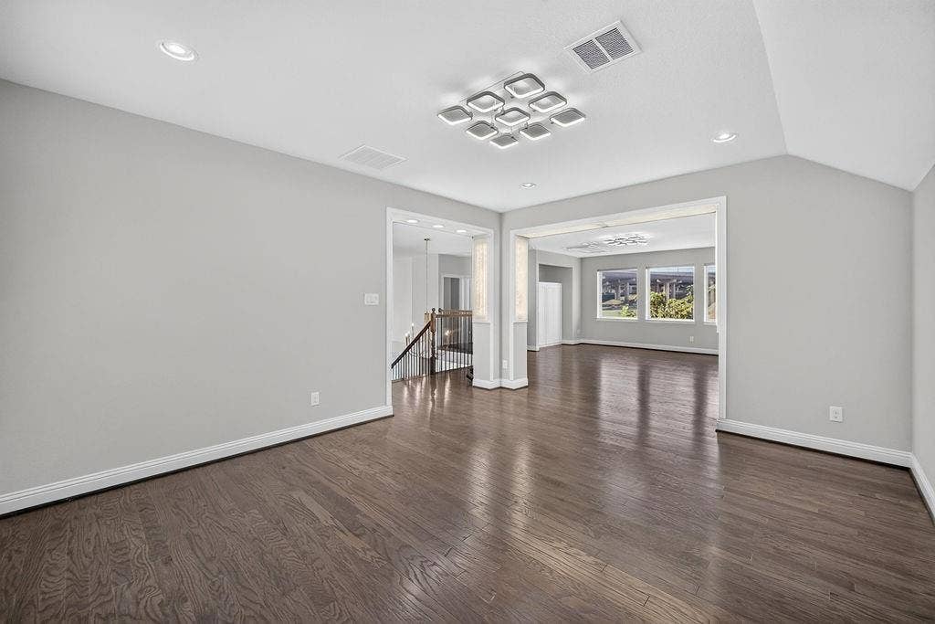 Interior space featuring dark wood-finish flooring, vaulted ceilings, recessed lighting, and a contemporary geometric flush-mount light fixture