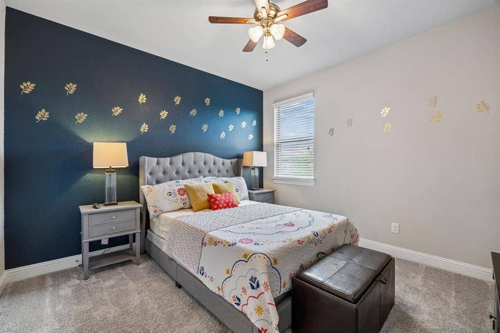 Upstairs guest bedroom with accent wall and ceiling fan