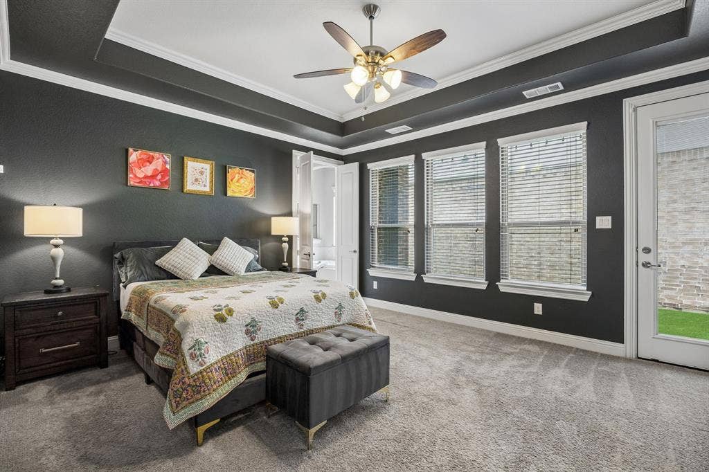 Primary bedroom with a panned ceiling, crown molding and door to back patio