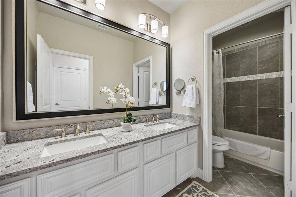 Upstairs guest bathroom with double sinks and shower/tub combo