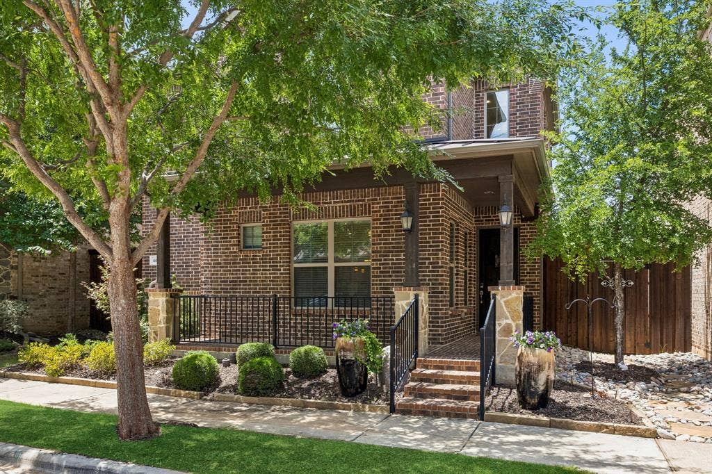 Front view showcasing lush landscaping and covered front porch