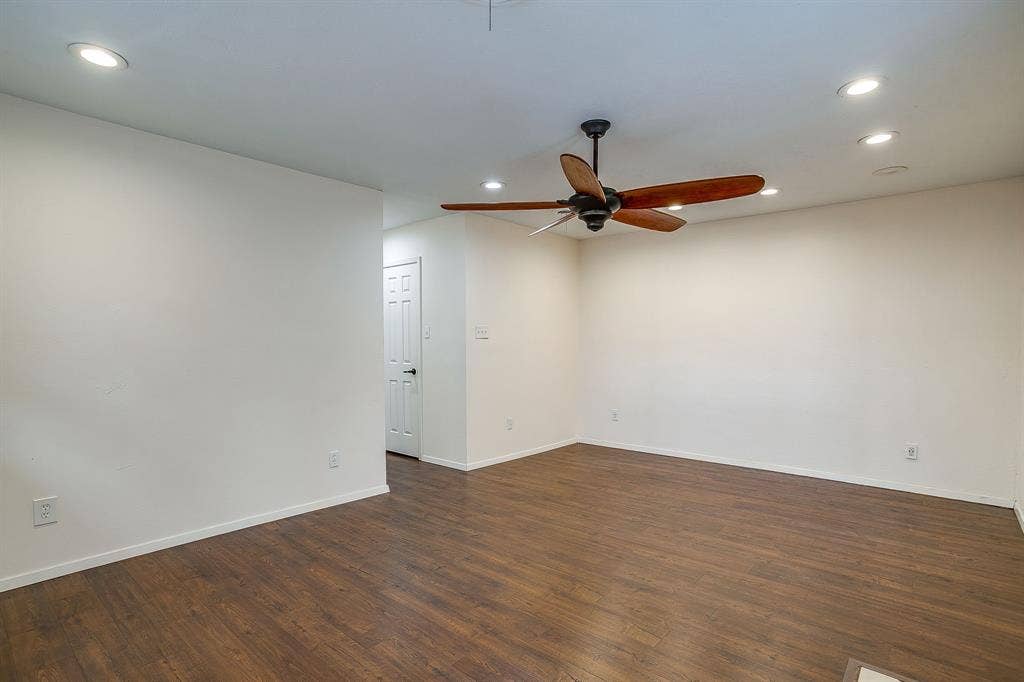 Wood-finish flooring, recessed lighting, ceiling fan with wood-look blades, white paneled interior door, and white walls