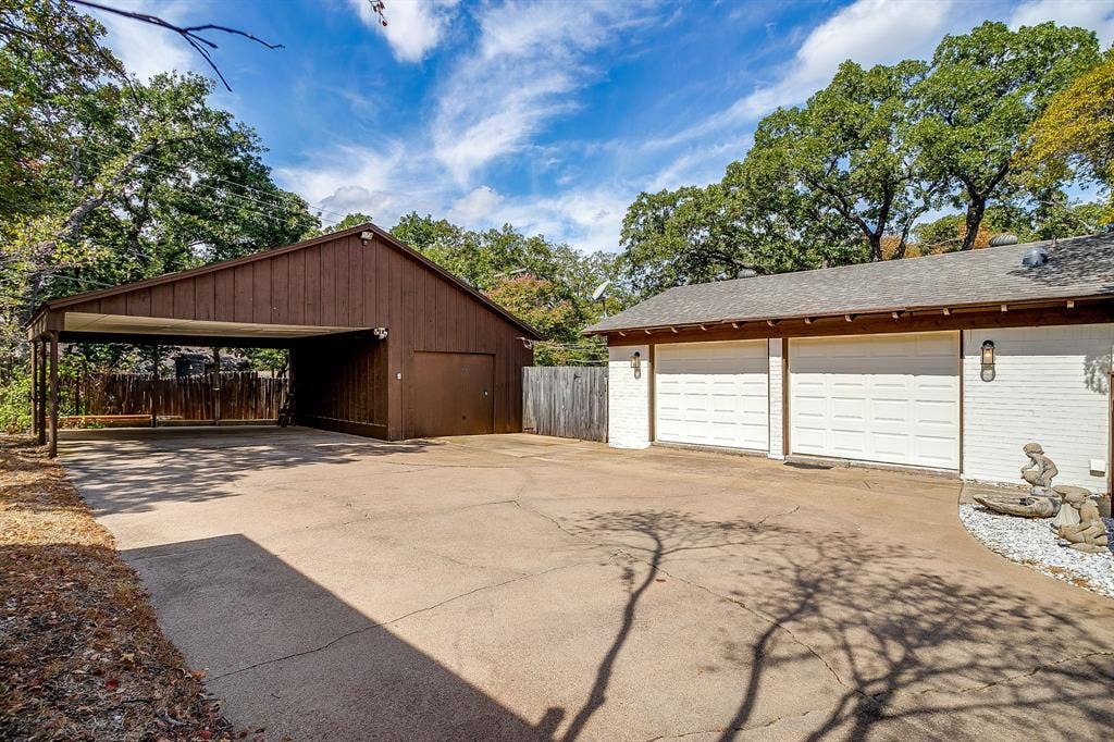 Detached carport with covered parking, separate garage door, concrete driveway, and two-car attached garage with white paneled doors