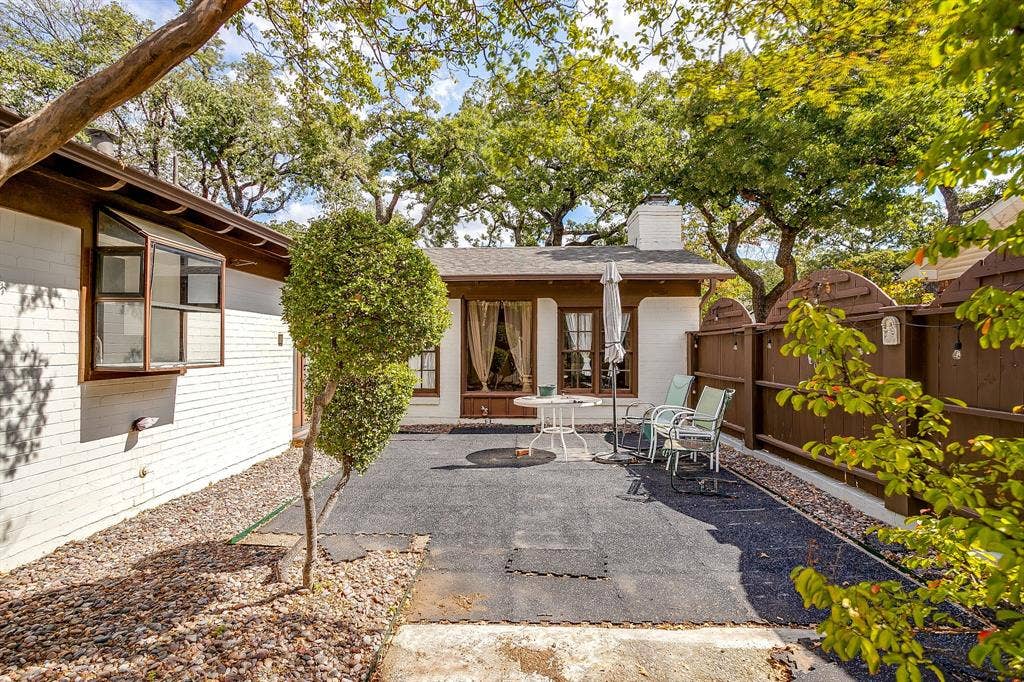 Private patio space featuring a solid privacy fence and mature trees