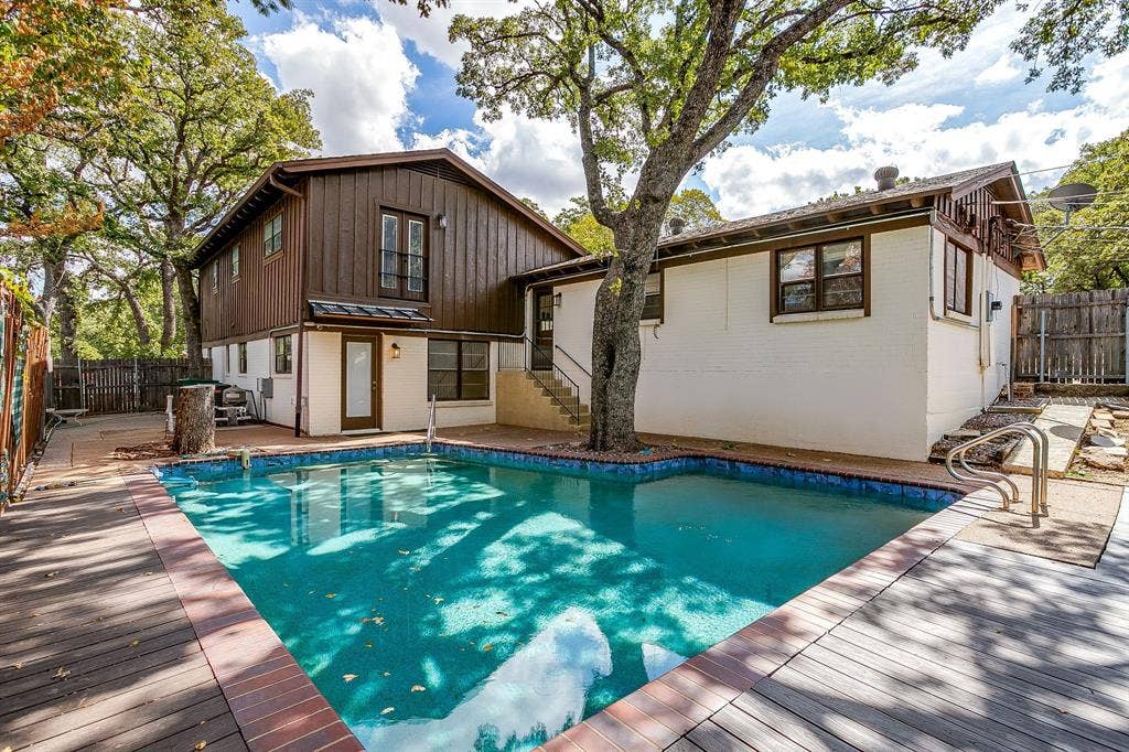 In-ground swimming pool with a surrounding wood-finish deck and brick trim