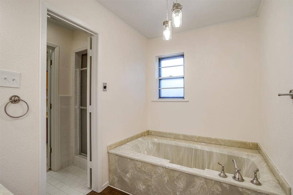 Built-in soaking tub with a stone-finish surround, paired with a window and two pendant light fixtures