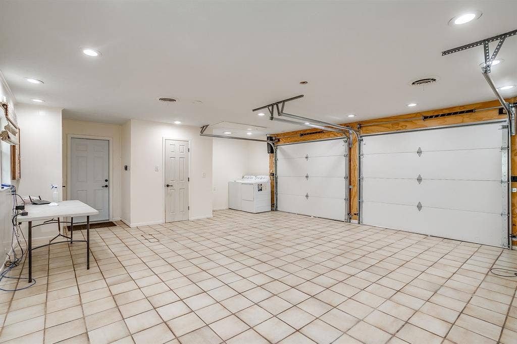 Spacious garage with light-toned tiled flooring, recessed ceiling lighting, and two individual garage doors