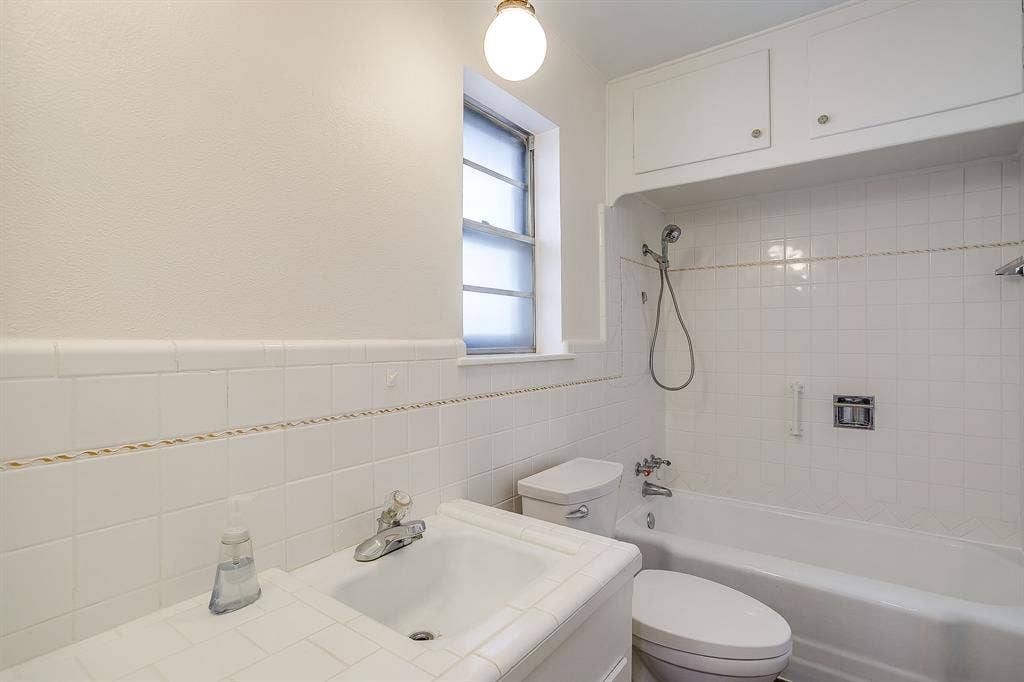 White tile shower and tub surround with integrated storage cabinetry