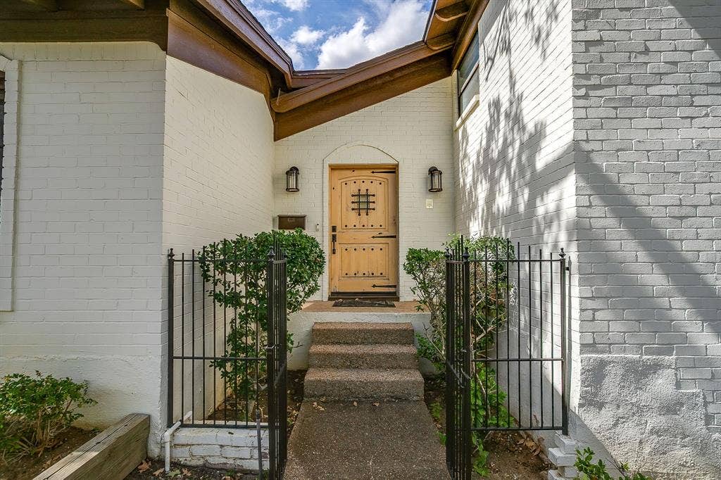 Painted brick exterior with a wood entry door featuring decorative ironwork and black sconces