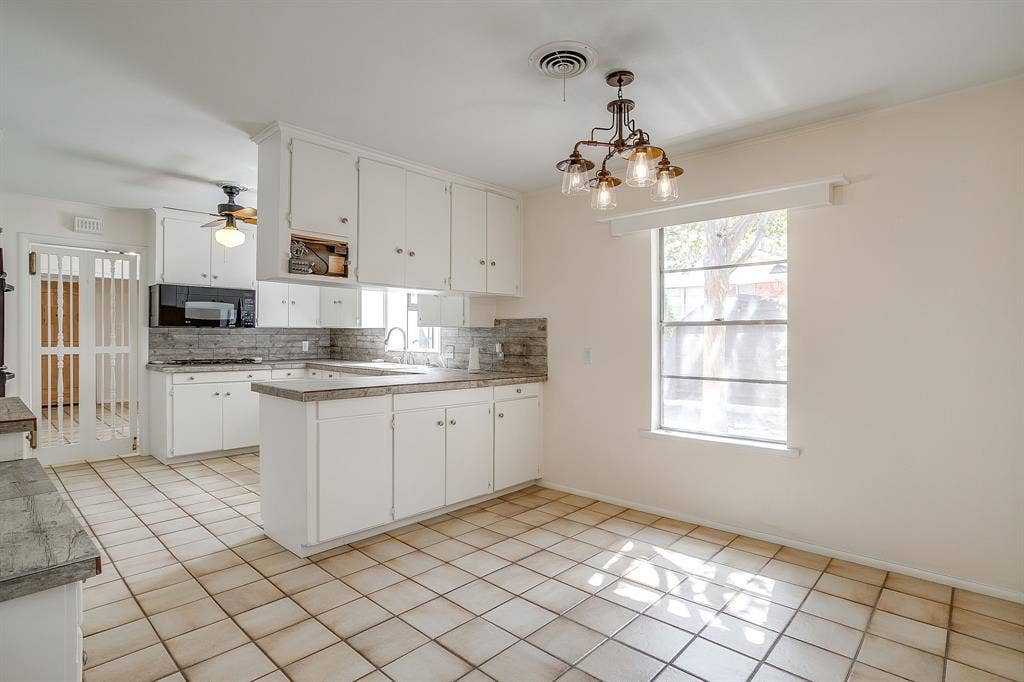 Kitchen featuring white cabinetry, tile backsplash, built-in microwave, U-shaped counter space, and tile flooring
