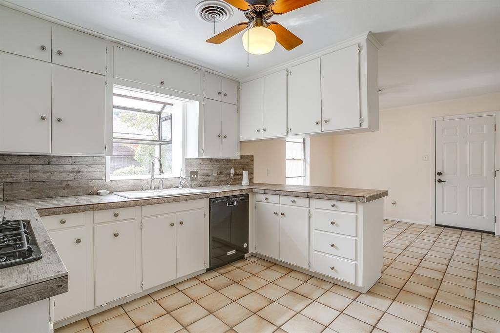 Kitchen featuring white cabinetry with silver-tone hardware, wood-finish countertops, and a tile backsplash
