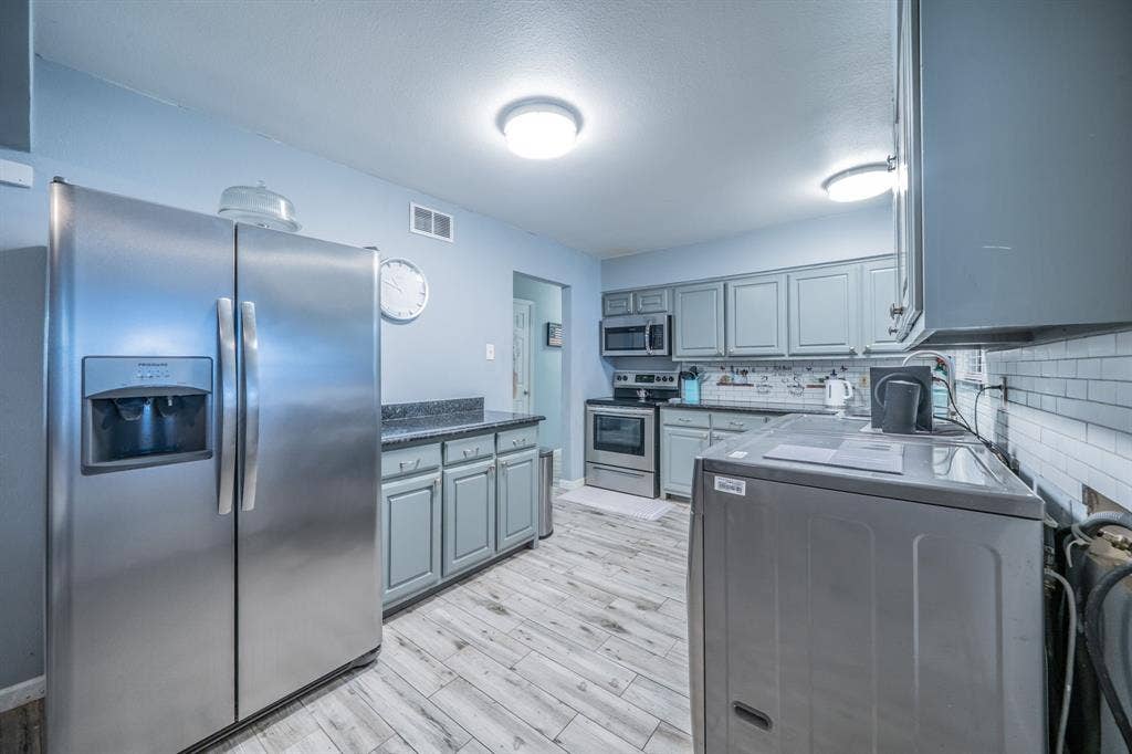 1938 Balla Way, Grand Prairie, TX 75051 Kitchen featuring stainless steel appliances, wood-finish flooring, gray cabinetry, dark countertops, and a subway tile backsplash