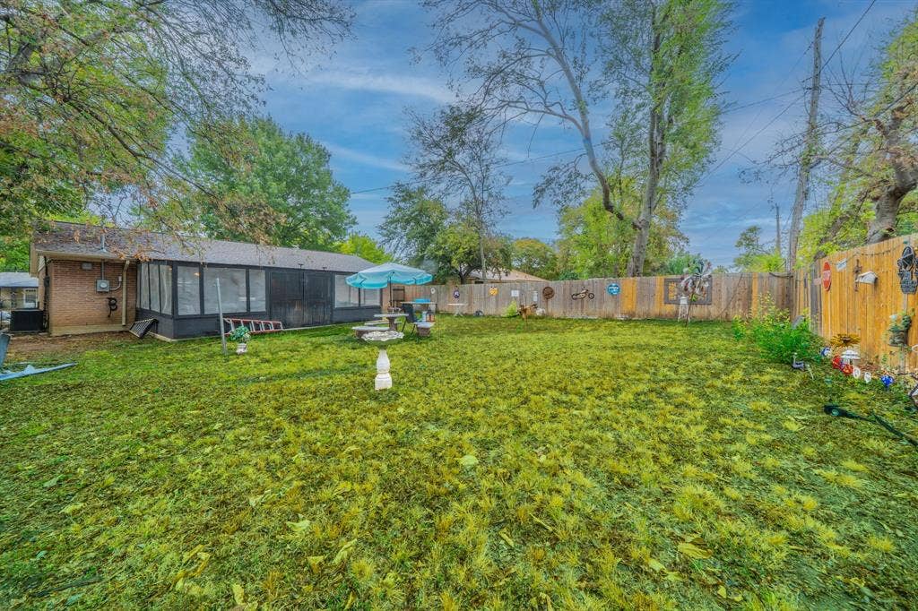 1938 Balla Way, Grand Prairie, TX 75051 Expansive backyard featuring a manicured lawn, wood fencing, and a sunroom addition