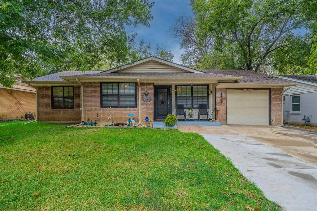 1938 Balla Way, Grand Prairie, TX 75051 Charming brick ranch home featuring a welcoming front elevation with a covered entry portico, black-trimmed windows, and a two-car attached garage