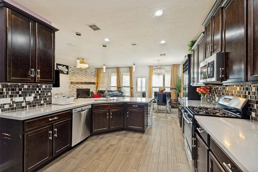 818 Black Hawk Drive, Princeton, TX 75407 Kitchen with dark wood-finish cabinetry, light-toned countertops, and a patterned tile backsplash