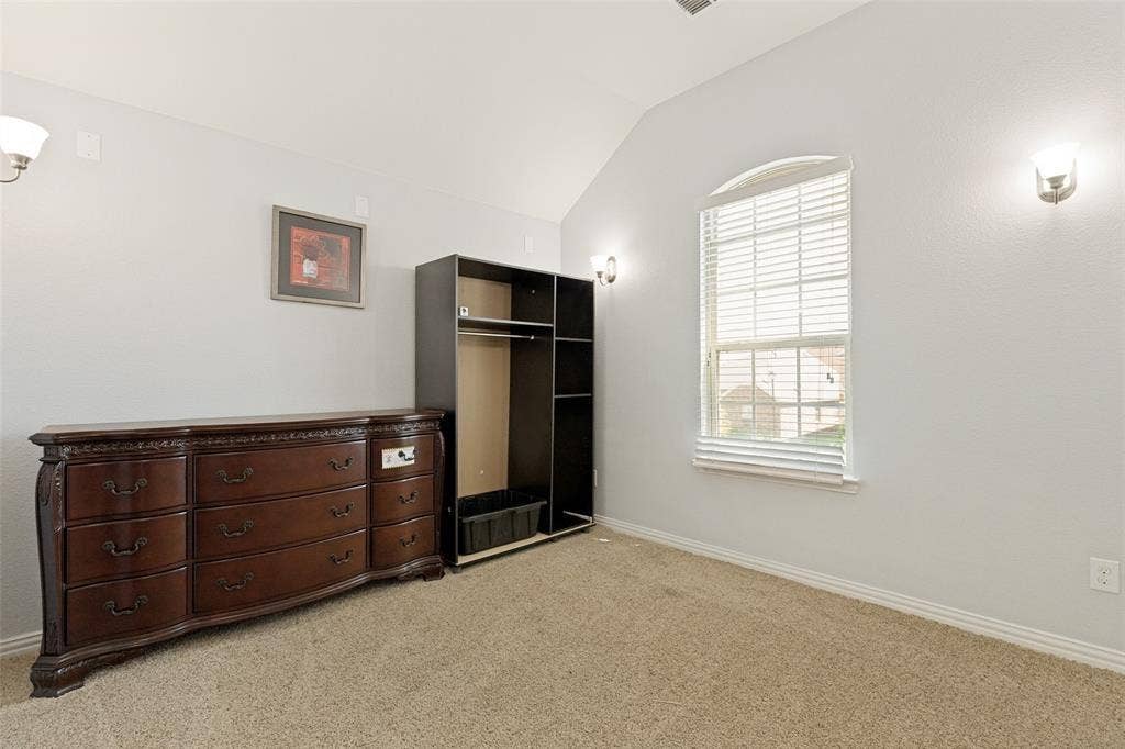 818 Black Hawk Drive, Princeton, TX 75407 Vaulted ceiling room with an arched window, wall-mounted sconces, and carpeting