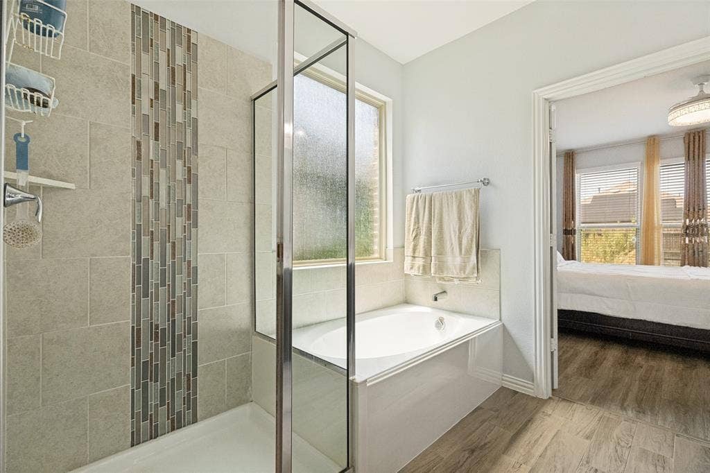 818 Black Hawk Drive, Princeton, TX 75407 Shower-tub combination with glass enclosure, decorative tile accent, and a privacy window