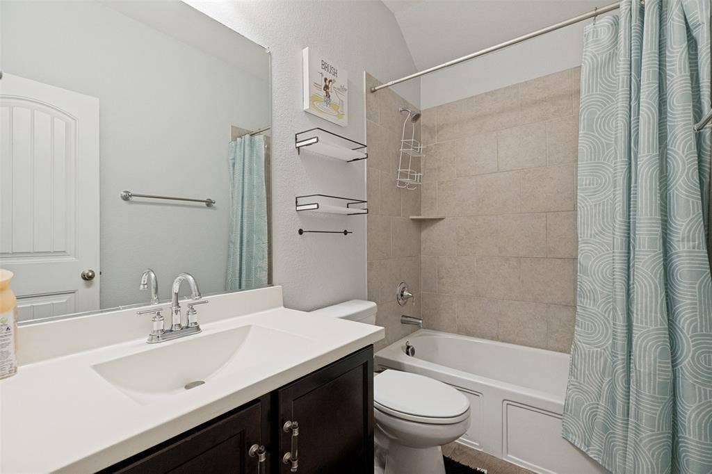 818 Black Hawk Drive, Princeton, TX 75407 Bathroom featuring a single vanity with a white countertop, chrome fixtures, a shower/tub combination with tiled surround, and built-in shelving