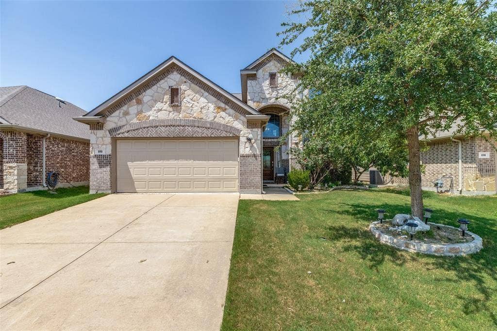 818 Black Hawk Drive, Princeton, TX 75407 Stone and brick facade with an arched entrance, a concrete driveway, and an integrated garage