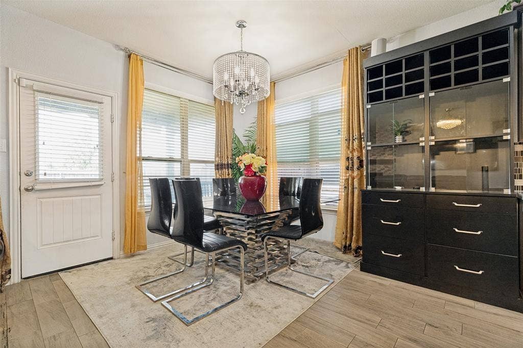 818 Black Hawk Drive, Princeton, TX 75407 Wood-finish flooring, multiple windows with blinds, a built-in cabinetry unit, and a chandelier fixture