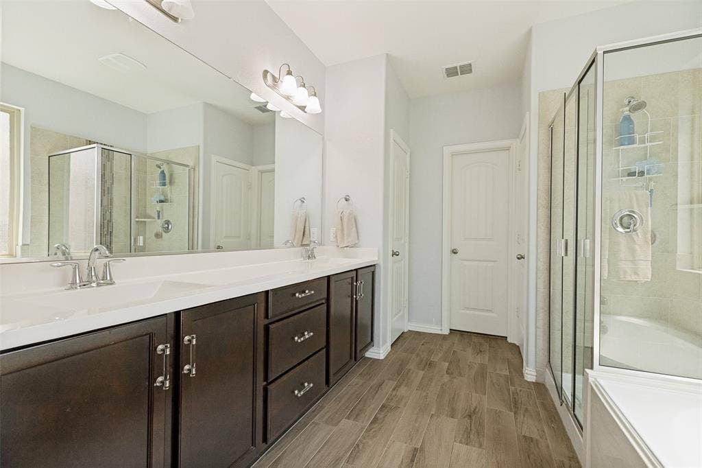 818 Black Hawk Drive, Princeton, TX 75407 Dual vanity with white countertops, dark wood-finish cabinetry, and chrome fixtures