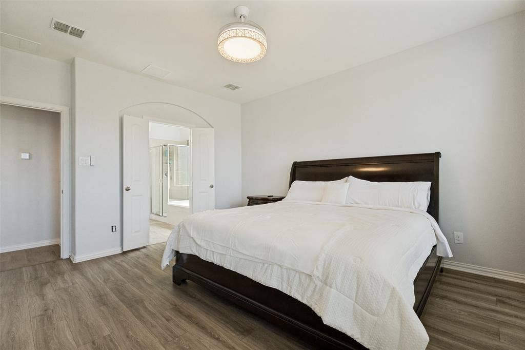 818 Black Hawk Drive, Princeton, TX 75407 Wood-finish flooring throughout, bright white walls, contemporary ceiling fan with integrated lighting, and an arched doorway leading to an additional space