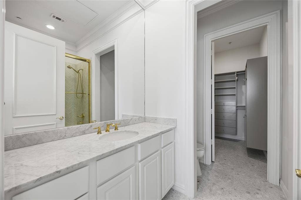 3535 Gillespie Street, #507, Dallas, TX 75219 White vanity with a stone countertop and gold-finish fixtures