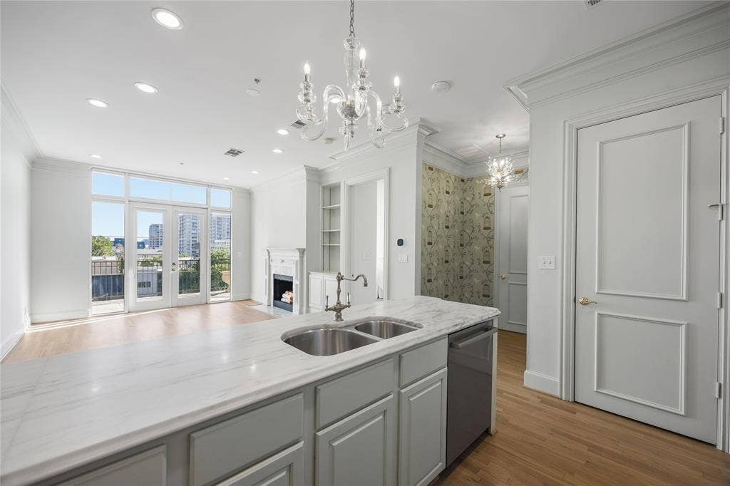 3535 Gillespie Street, #507, Dallas, TX 75219 Open-concept kitchen featuring white cabinetry, stainless steel appliances, and a central island with a sink